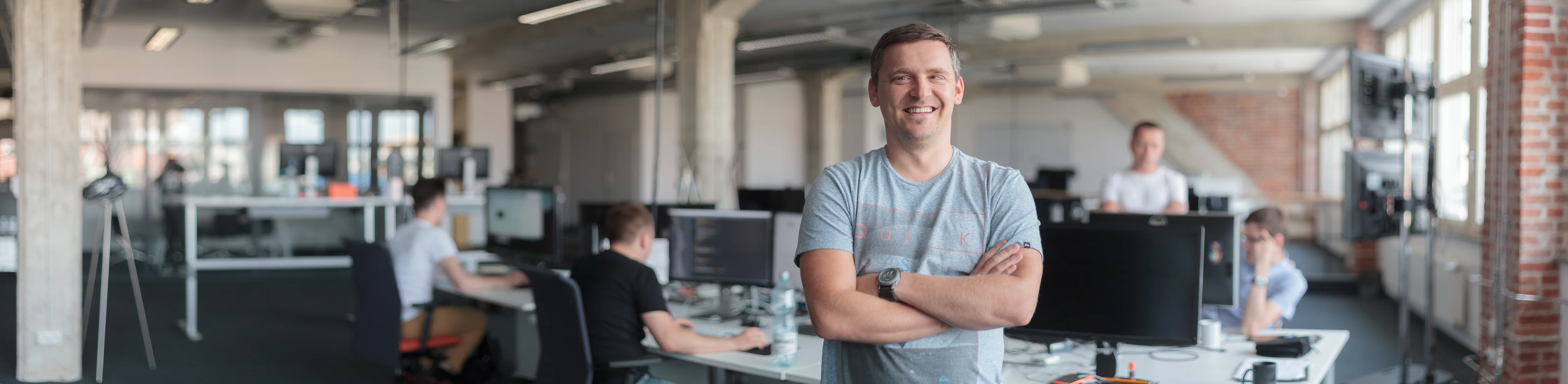 Dariusz Frączyk smiling with his arms crossed in an office